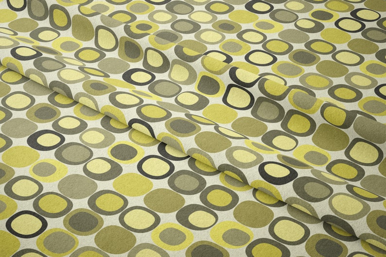 May include: A fabric with a repeating pattern of yellow, green, and black circles on a white background.