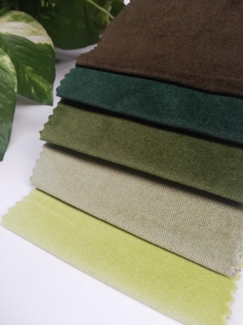 May include: A stack of six fabric swatches in various shades of green, brown, and beige. The swatches are arranged from darkest to lightest, with the brown swatch on top and the lightest beige swatch on the bottom.