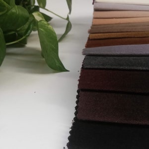 May include: A collection of fabric swatches in various shades of brown, gray, and black. The swatches are arranged in a row, with the lightest shade at the top and the darkest shade at the bottom.