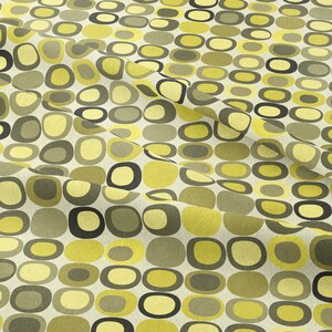 May include: A fabric with a repeating pattern of yellow and green rounded shapes on a white background.