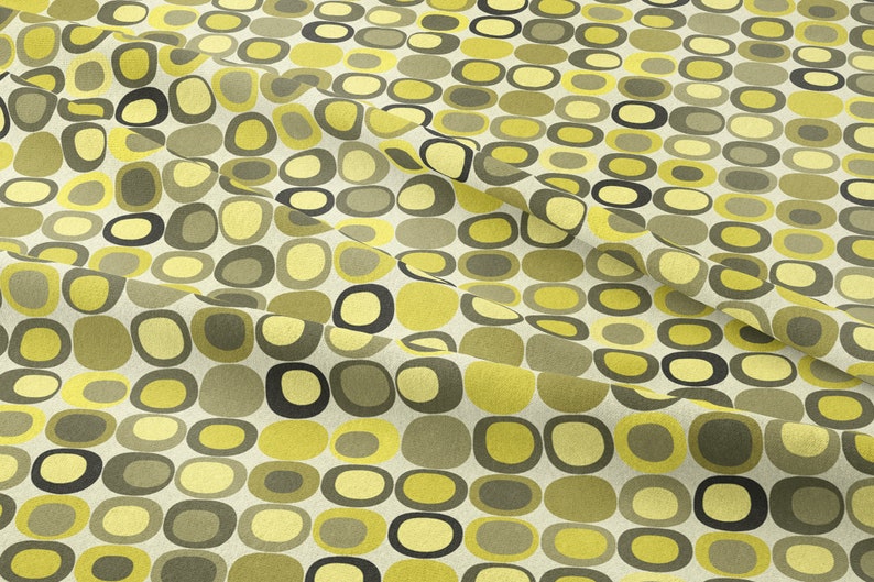 May include: A fabric with a repeating pattern of yellow and green rounded shapes on a white background.