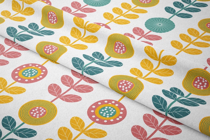 May include: White fabric with a repeating floral pattern. The design features stylized flowers and leaves in yellow, teal, pink, and green. The fabric is folded, showing the pattern's repeat.