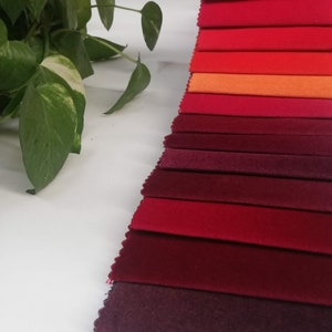 May include: A collection of fabric swatches in various shades of red, orange, and burgundy. The swatches are arranged in a gradient from light to dark.