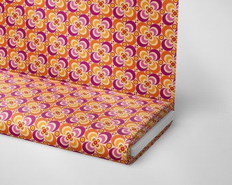 Puede incluir: Una tela con un patrón repetido de flores estilizadas de color naranja, rosa y amarillo. La tela está doblada y enrollada.