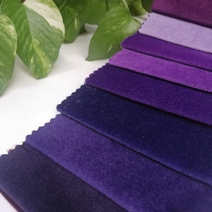 May include: A collection of fabric swatches in various shades of purple, ranging from light lavender to deep indigo. The swatches are arranged in a gradient, with the lightest shade at the top and the darkest shade at the bottom.
