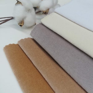 May include: A collection of six fabric swatches in various shades of brown, beige, and white. The swatches are arranged in a stack, with the white swatch on top and the darkest brown swatch on the bottom.