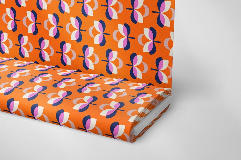 K&ouml;nnte beinhalten: Orangener Stoff mit einem sich wiederholenden Muster aus stilisierten Blumenformen in Wei&szlig;, Marineblau und Rosa. Der Stoff ist aufgerollt und zeigt das Muster auf der Oberseite und der Seite. Das Design ist im Retro-Stil der Moderne der Mitte des Jahrhunderts.