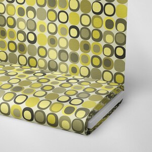 May include: A roll of fabric with a retro pattern of yellow, green, and black circles and squares on a white background.