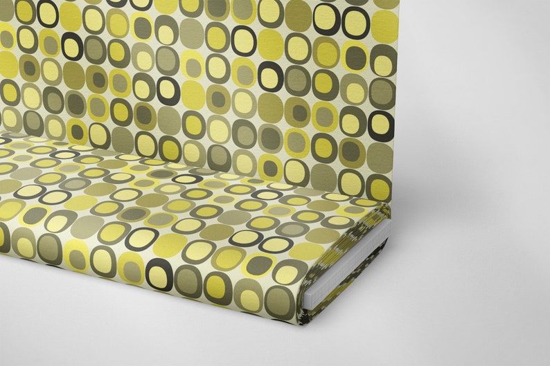May include: A roll of fabric with a retro pattern of yellow, green, and black circles and squares on a white background.