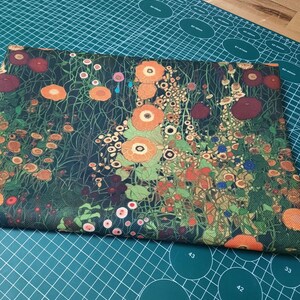 May include: A rectangular piece of fabric featuring a dense, dark green background covered in a vibrant floral pattern. The design includes numerous orange, red, and yellow flowers with green stems and foliage, creating a detailed botanical print.