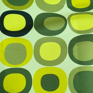 May include: A green and yellow fabric with a repeating pattern of circles. The circles are in different sizes and have a concentric ring design.