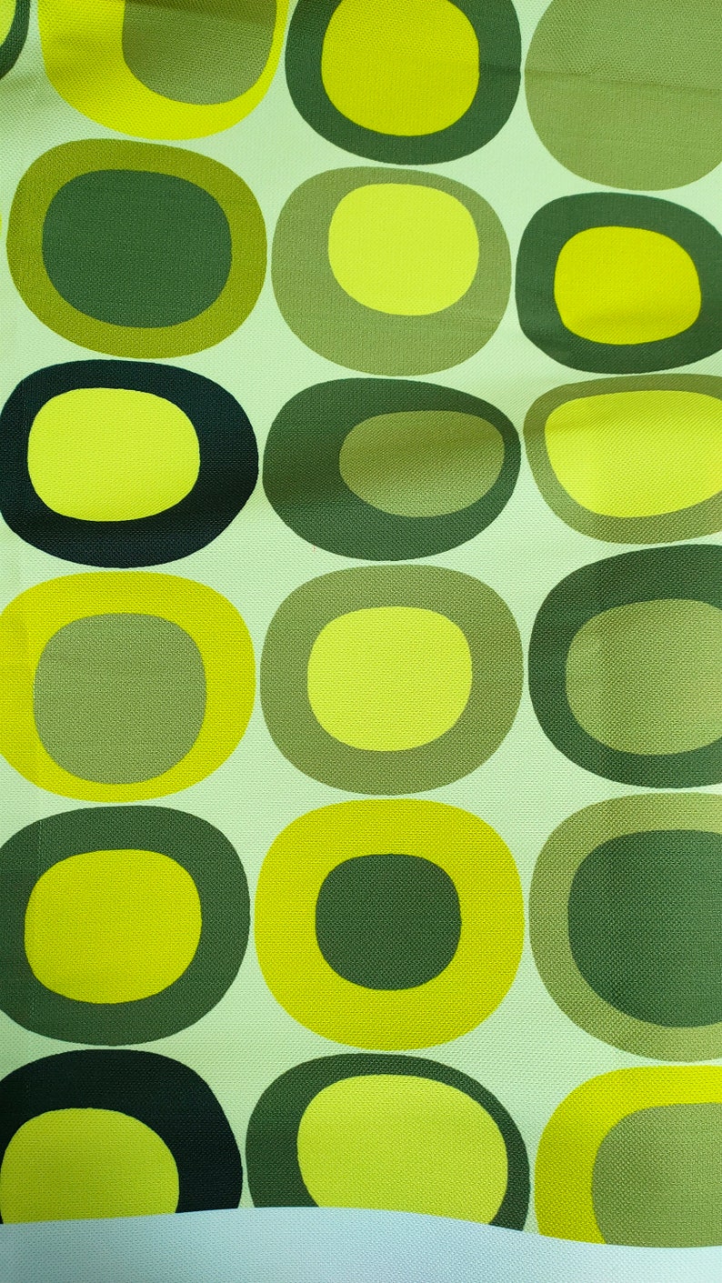 May include: A green and yellow fabric with a repeating pattern of circles. The circles are in different sizes and have a concentric ring design.