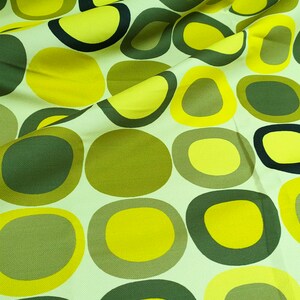 May include: A fabric with a repeating pattern of green and yellow circles. The circles are of varying sizes and are arranged in a random pattern.