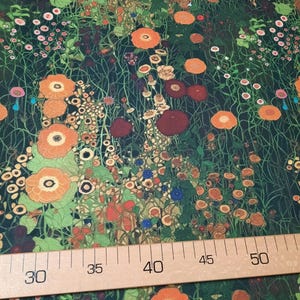 May include: A fabric featuring a dense floral pattern with orange, red, and pink flowers on a dark green background, positioned above a wooden ruler showing measurements from 30 to 50 centimeters, indicating the scale of the botanical print.