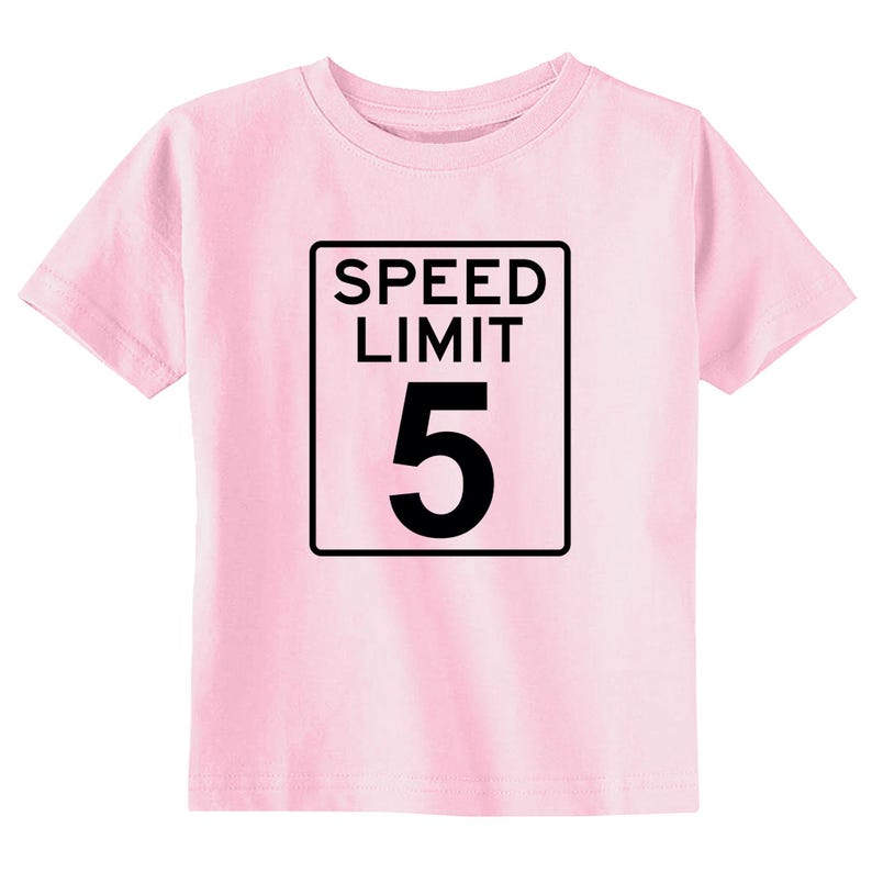 Pode incluir: Uma t-shirt de manga curta em rosa claro com uma impress&atilde;o gr&aacute;fica preta de um sinal retangular de limite de velocidade. O sinal cont&eacute;m o texto SPEED LIMIT em letras mai&uacute;sculas pretas acima de um grande n&uacute;mero 5 preto.