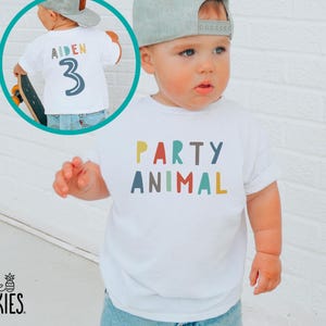 May include: A white short-sleeved t-shirt featuring the text PARTY ANIMAL in multicolored block letters on the front. An inset circle shows the back of the shirt with the name AIDEN and the number 3 printed in a similar multicolored style.