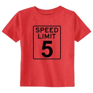 Pode incluir: Uma t-shirt de manga curta em vermelho mesclado com uma impress&atilde;o gr&aacute;fica preta de um sinal de tr&acirc;nsito retangular. O sinal tem uma borda preta e cont&eacute;m o texto SPEED LIMIT seguido pelo n&uacute;mero 5 grande centrado no design.