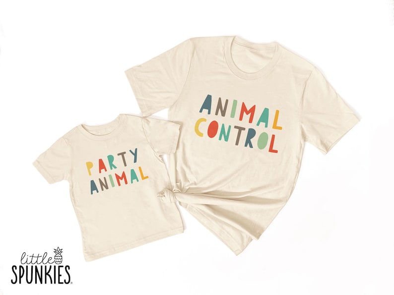 May include: Two cream-colored short-sleeve t-shirts. The smaller shirt features the text "PARTY ANIMAL" in multicolored letters. The larger shirt features the text "ANIMAL CONTROL" in multicolored letters. The text "little SPUNKIES" is in the corner.