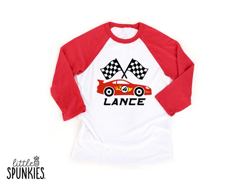 May include: A white baseball-style shirt with red three-quarter length sleeves. The front features a graphic of a red race car with the number 4, two checkered flags, and the name LANCE printed in black text below the car design.