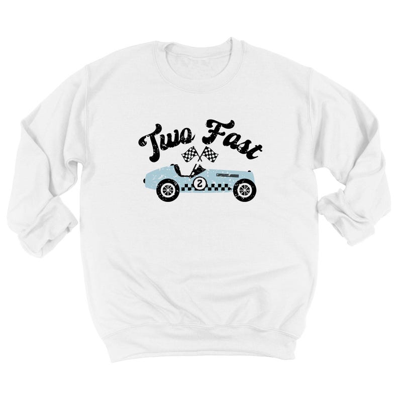May include: A white long-sleeve sweatshirt featuring a graphic of a light blue vintage race car with the number two on the side, two checkered flags above it, and the black text Two Fast written in a distressed font style across the chest.