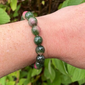 May include: A green and pink gemstone bracelet with faceted beads. The bracelet is made of natural stones and is a beautiful example of handmade jewellery.
