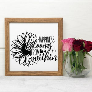 May include: A framed print with a black and white sunflower graphic and the text "Happiness blooms from within".