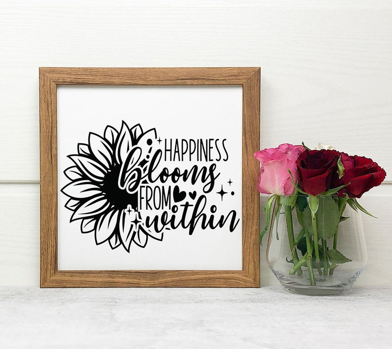 May include: A framed print with a black and white sunflower graphic and the text "Happiness blooms from within".