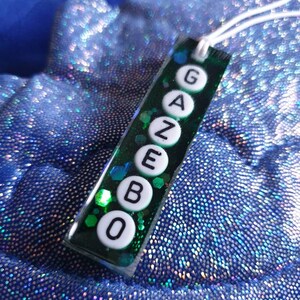 May include: A green and white resin pendant with the word "GAZEBO" spelled out in white letters.