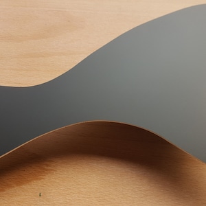 May include: A grey guitar pickguard with a distinctive, curved form and three screw holes. The pickguard is made of a smooth, solid material and is designed to protect the guitar's body. It is a replacement part for electric guitars.