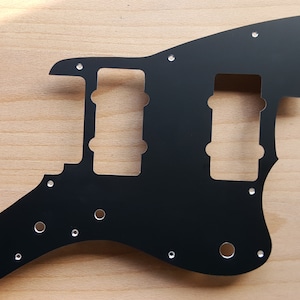 May include: Black guitar pickguard with multiple screw holes and cutouts for pickups and controls.
