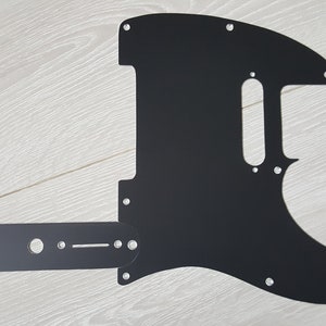 May include: Black guitar pickguard with cutouts for a single coil pickup, a humbucker pickup, and a control plate. The pickguard is made of a durable material and is designed to fit a standard electric guitar.