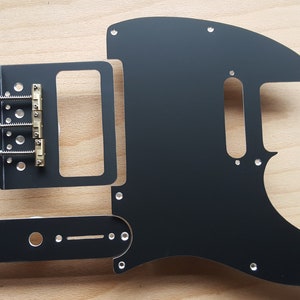May include: Black guitar pickguard with a bridge pickup and control plate. The pickguard is made of metal and has a smooth, matte finish.