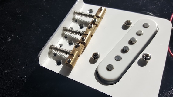 テレキャスタースタイルのギター用の白いブリッジ。2 mmの光沢のある