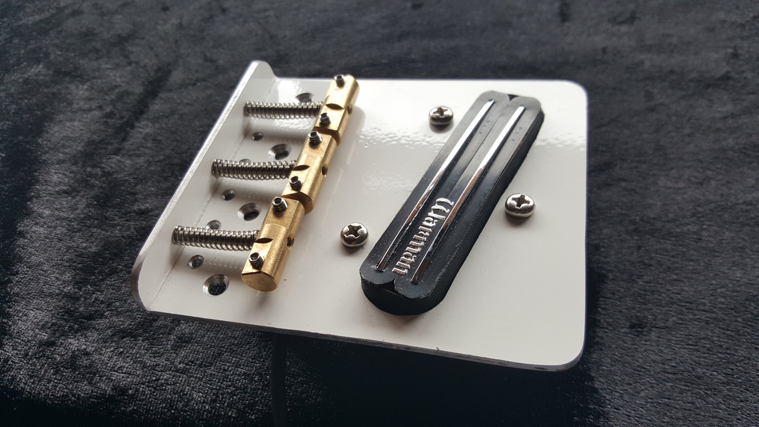 テレキャスタースタイルのギター用の白いブリッジ。2 mmの光沢のある