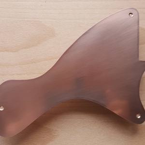May include: A copper-coloured metal guitar pickguard with a unique shape and three small holes.