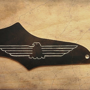 May include: Black leather guitar pickguard with a white eagle design and the text "Hand made and Engraved by ghost CUSTOM GUITARS".
