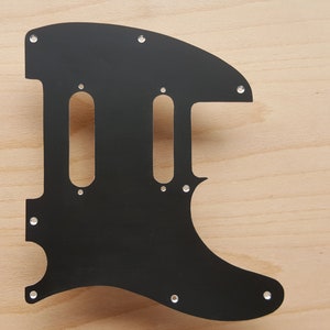 May include: Black guitar pickguard with two pickup cutouts and multiple screw holes.
