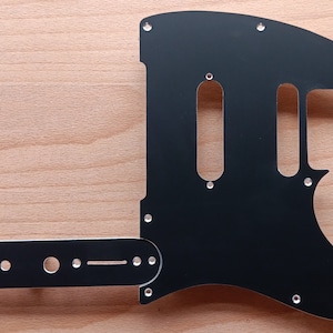 May include: Black guitar pickguard with two humbucker pickup cutouts and a control plate. The pickguard is made of metal and has a smooth, shiny finish.