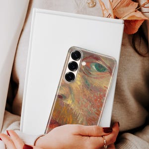 May include: A smartphone case featuring a vibrant, textured impressionist-style painting of a human eye with warm tones of orange, yellow, and brown, contrasted by a green iris. The case has a vertical triple-lens camera cutout on the upper left.