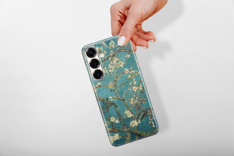 May include: A rectangular smartphone case featuring a teal blue background with a detailed print of brown tree branches and white almond blossoms. The case has three circular camera lens cutouts arranged vertically on the upper left side.