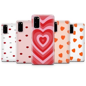 Puede incluir: Cinco fundas de teléfono diferentes con varios diseños. Las fundas son transparentes y muestran un diseño de corazón rosa y rojo, un diseño de corazón rojo y rosa, un fondo blanco con corazones naranjas, un fondo rosa con labios rojos y un fondo blanco con corazones rojos.