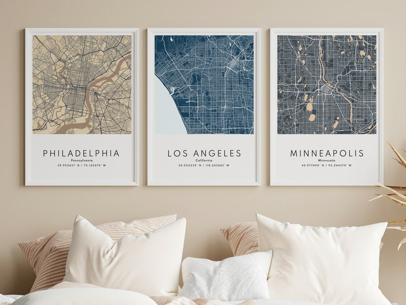 May include: Three framed city maps with white frames and a beige background. The maps are of Philadelphia, Los Angeles, and Minneapolis. The maps are in a blue and beige color scheme.