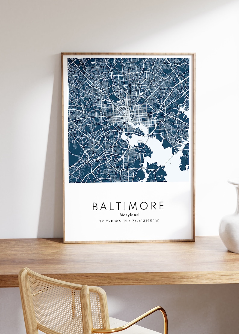 May include: A framed map of Baltimore, Maryland, in a dark blue color scheme. The map shows the city's streets and waterways. The text below the map reads "Baltimore, Maryland, 39.290386&deg; N / 76.612190&deg; W".