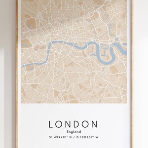May include: A beige and blue map print of London, England. The map shows the city streets and the River Thames. The text below the map reads "LONDON, England, 51.499491&deg; N / 0.120837&deg; W".