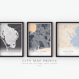 May include: Three framed city map prints. The maps are of St. Petersburg, Cape Town, and Boston. Each map is in a black frame and features a detailed street layout. The text "CITY MAP PRINTS" is displayed below the frames.