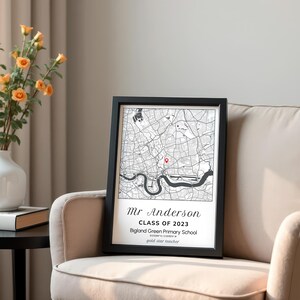 May include: A framed black and white map print with a red marker. The print includes the text "Mr Anderson Class of 2023 Bigland Green Primary School". The print is displayed on a beige armchair.