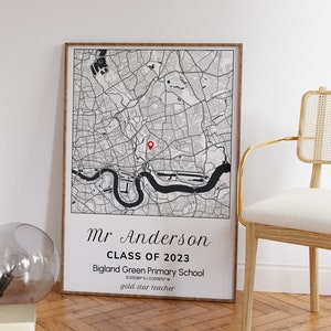 May include: A framed black and white map print featuring a detailed city map with a red marker. The print includes the text "Mr Anderson CLASS OF 2023 Bigland Green Primary School gold star teacher". The frame is a light brown color.