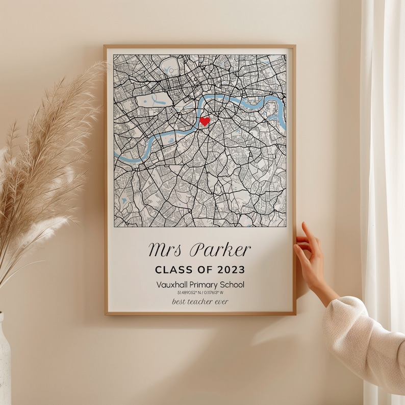 May include: Framed map print featuring a detailed black and white city map with a red heart marker. The print includes the text "Mrs Parker, Class of 2023, Vauxhall Primary School, 51.489062&deg; N / 0.10763&deg; W, best teacher ever."