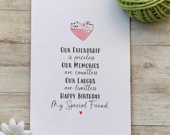 Op de afbeelding: Een witte wenskaart met de tekst "OUR FRIENDSHIP is priceless, OUR MEMORIES are countless, OUR LAUGHS are limitless, HAPPY BIRTHDAY My Special Friend." Een roze hart met bloemmotieven staat bovenaan. Groen touw en madeliefjes zijn ook aanwezig.