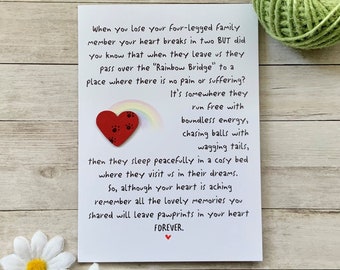 May include: A white card with a handwritten message about losing a pet. The card features a red heart with paw prints and a rainbow. The text reads: "When you lose your four-legged family member your heart breaks in two BUT did you know that when they leave us they pass over the "Rainbow Bridge" to a place where there is no pain or suffering? It's somewhere they run free with boundless energy, chasing balls with wagging tails, then they sleep peacefully in a cosy bed where they visit us in their dreams. So, although your heart is aching remember all the lovely memories you shared will leave pawprints in your heart FOREVER."